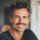 Homme souriant avec cheveux bouclés et barbe légère.